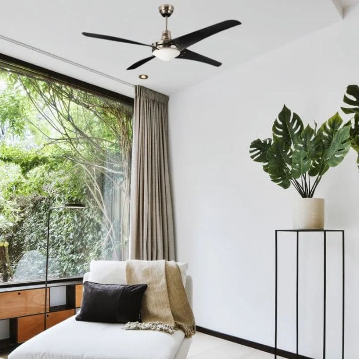 Salon moderne lumineux avec plafond inclinant, ventilateur silencieux au centre, grand baie vitrée et plantes d’intérieur. Meilleur rafraîchisseur d'air silencieux intégré naturellement dans la description.