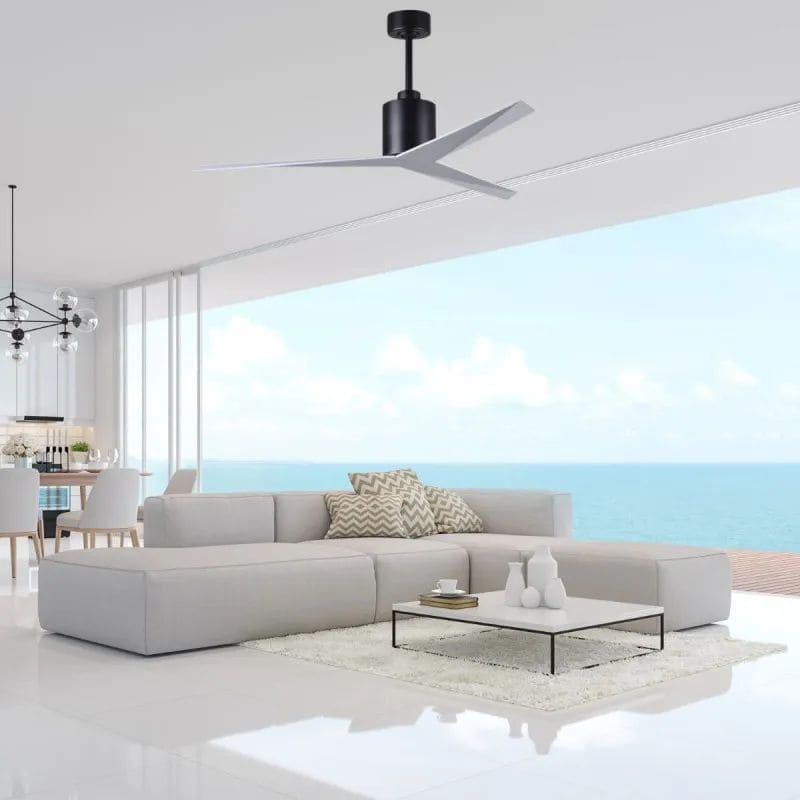 Ventilateur de plafond noir suspendu au centre d’un salon lumineux au style minimaliste, avec canapés gris, table basse et vue sur l’océan. Installer un ventilateur de plafond.